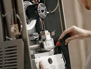 Furnace repair technician inspecting internal components and wiring in Lancaster, PA