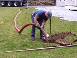 Septic pumping technician servicing a residential septic tank with a vacuum hose in Lancaster, PA