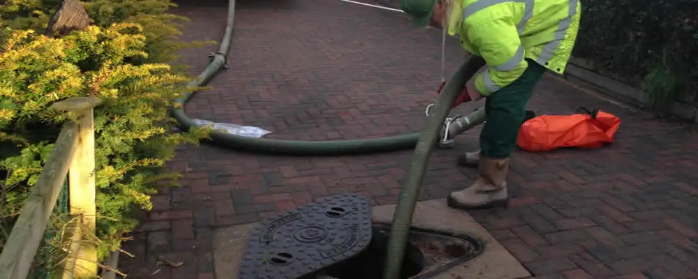 Septic tank cleaning technician servicing a septic tank with a vacuum hose in Lancaster, PA