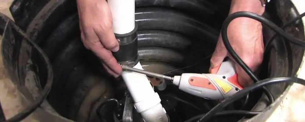 Sump pump installation technician connecting PVC discharge piping in Lancaster, PA